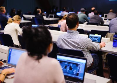 Attendees working on laptops during a workshop session at a conference