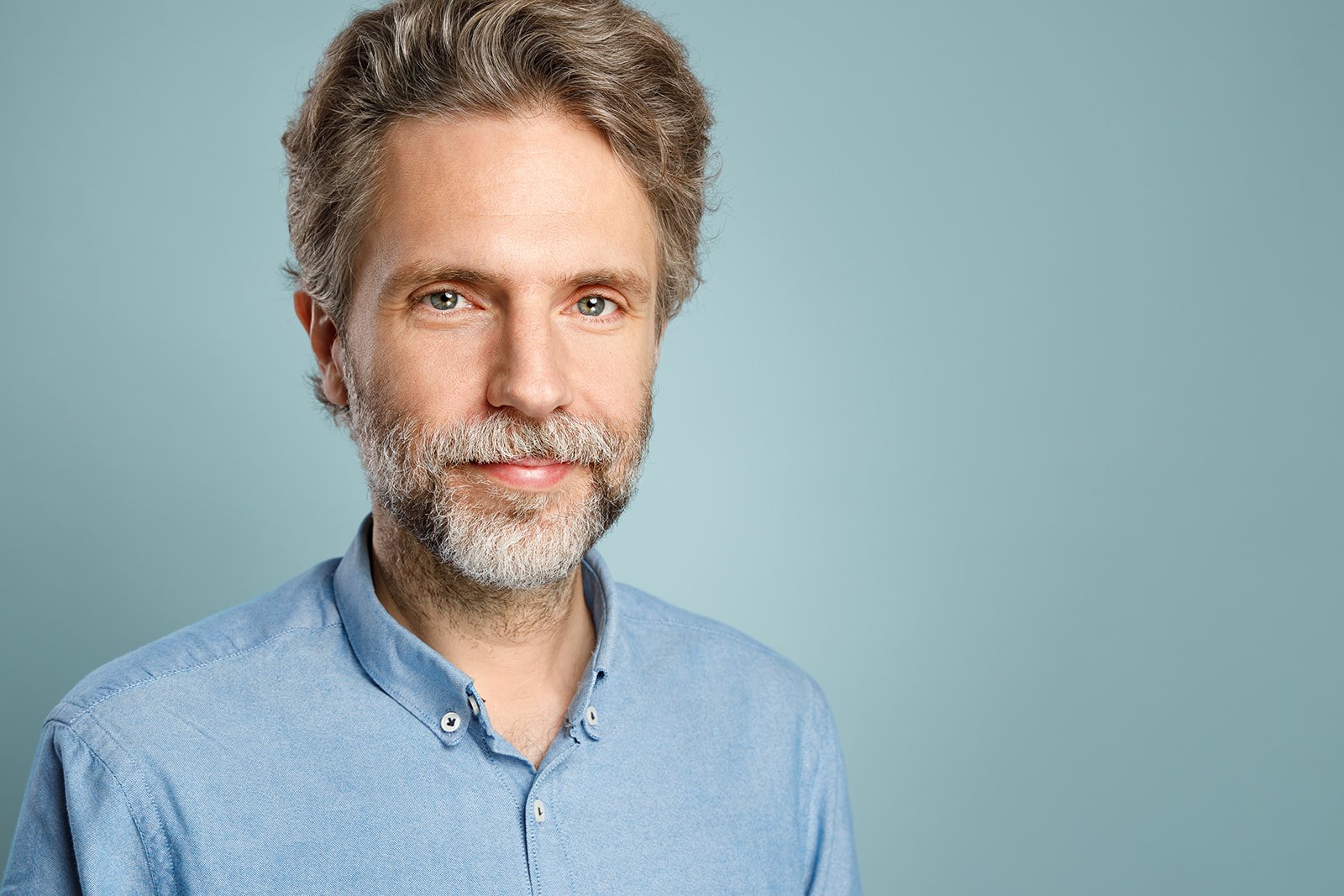 Trust-Inspiring Portrait of a Man – Empathetic and Professional Smiling man with a warm and empathetic expression, photographed in a minimalist studio – trustworthy professional portrait